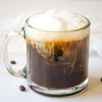 almond milk latte in glass cup with lots of foam