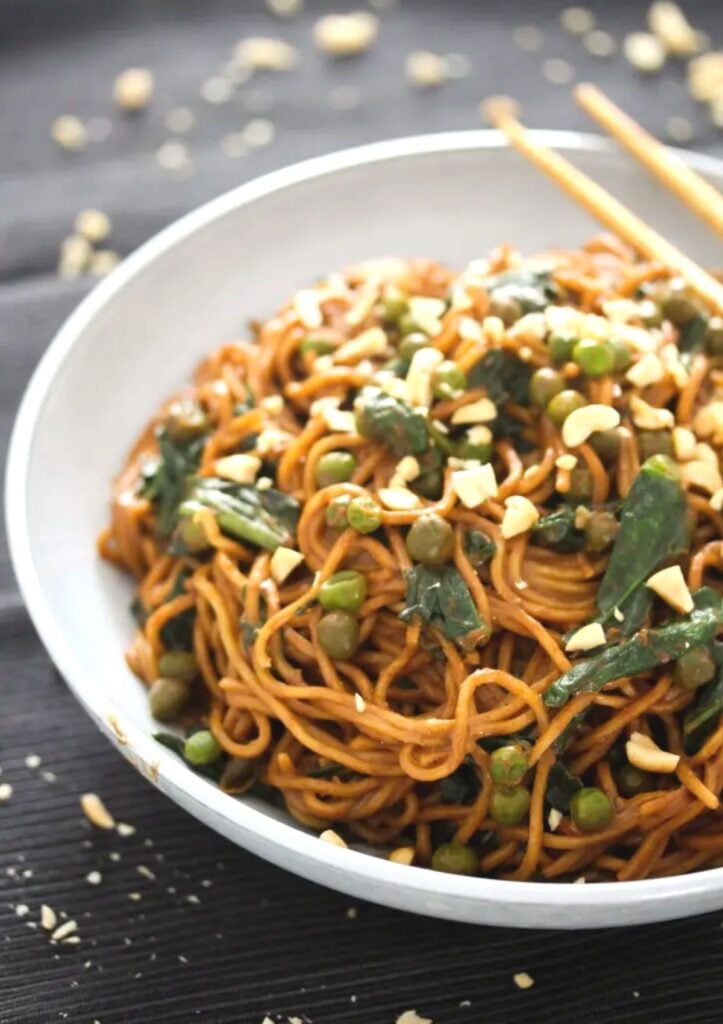 noodles covered in peanut butter sauce with peans and spinach