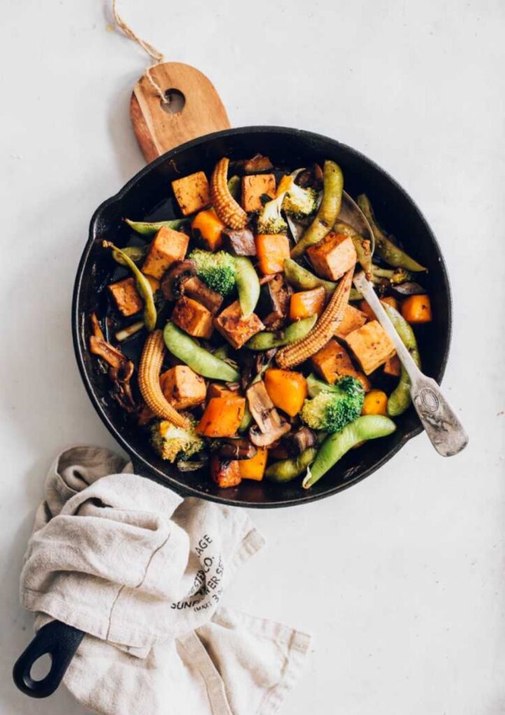 vegetable stir fry in pan with mini corn, tofu, broccoli, and snap peas