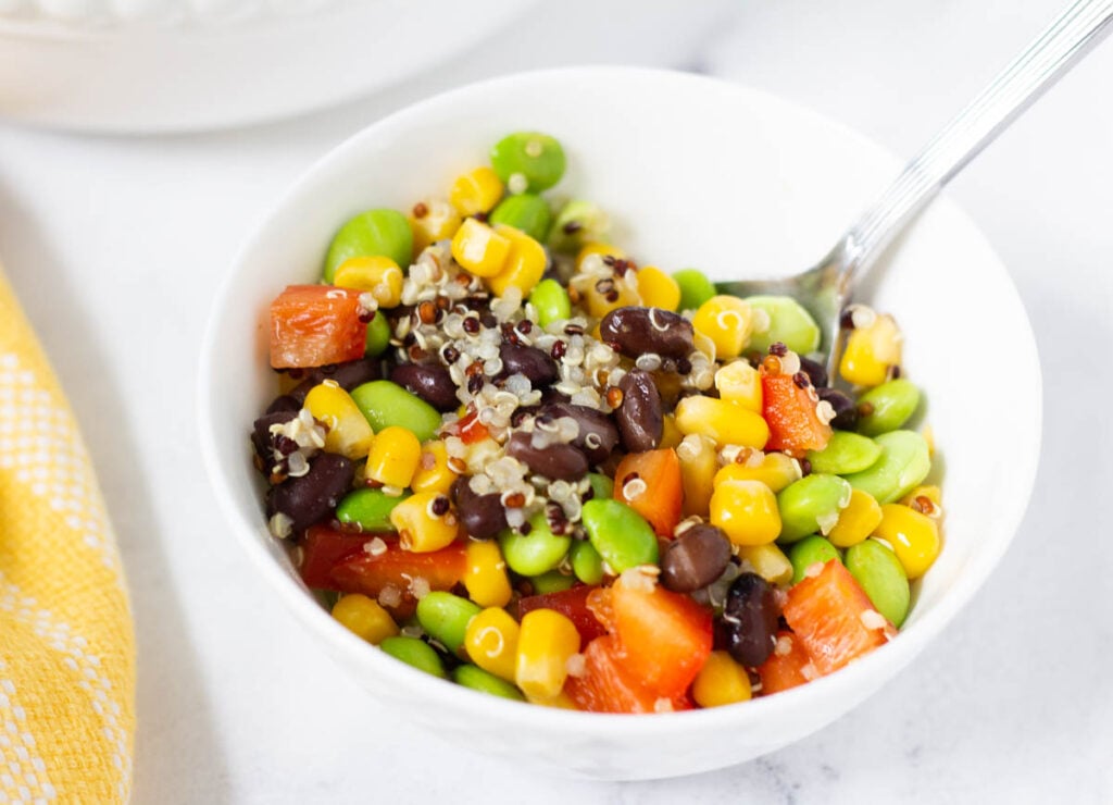 small white bowl filled with quinoa, edamame, corn and black beans