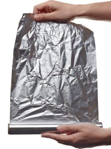 hands pulling roll of aluminum foil