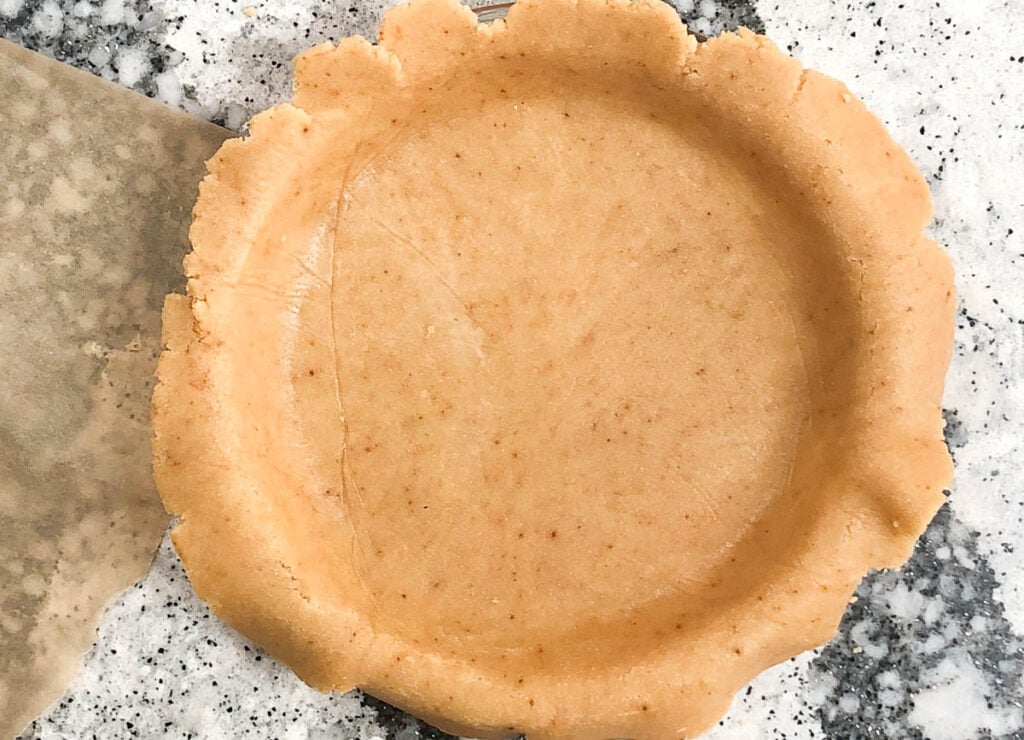 pie crust in pie pan, with extra hanging off the edges