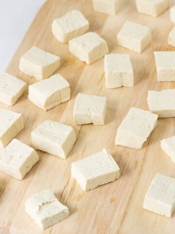 tofu block and tofu pieces on wood cutting board