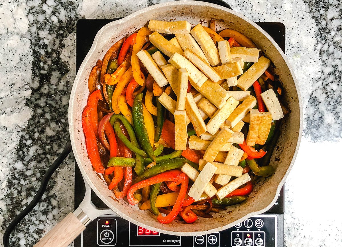 Large skillet with bell pepper slices on one side, and crispy tofu strips on the other.