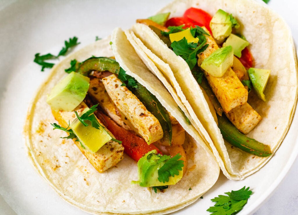 two corn tortillas filled with tofu and peppers