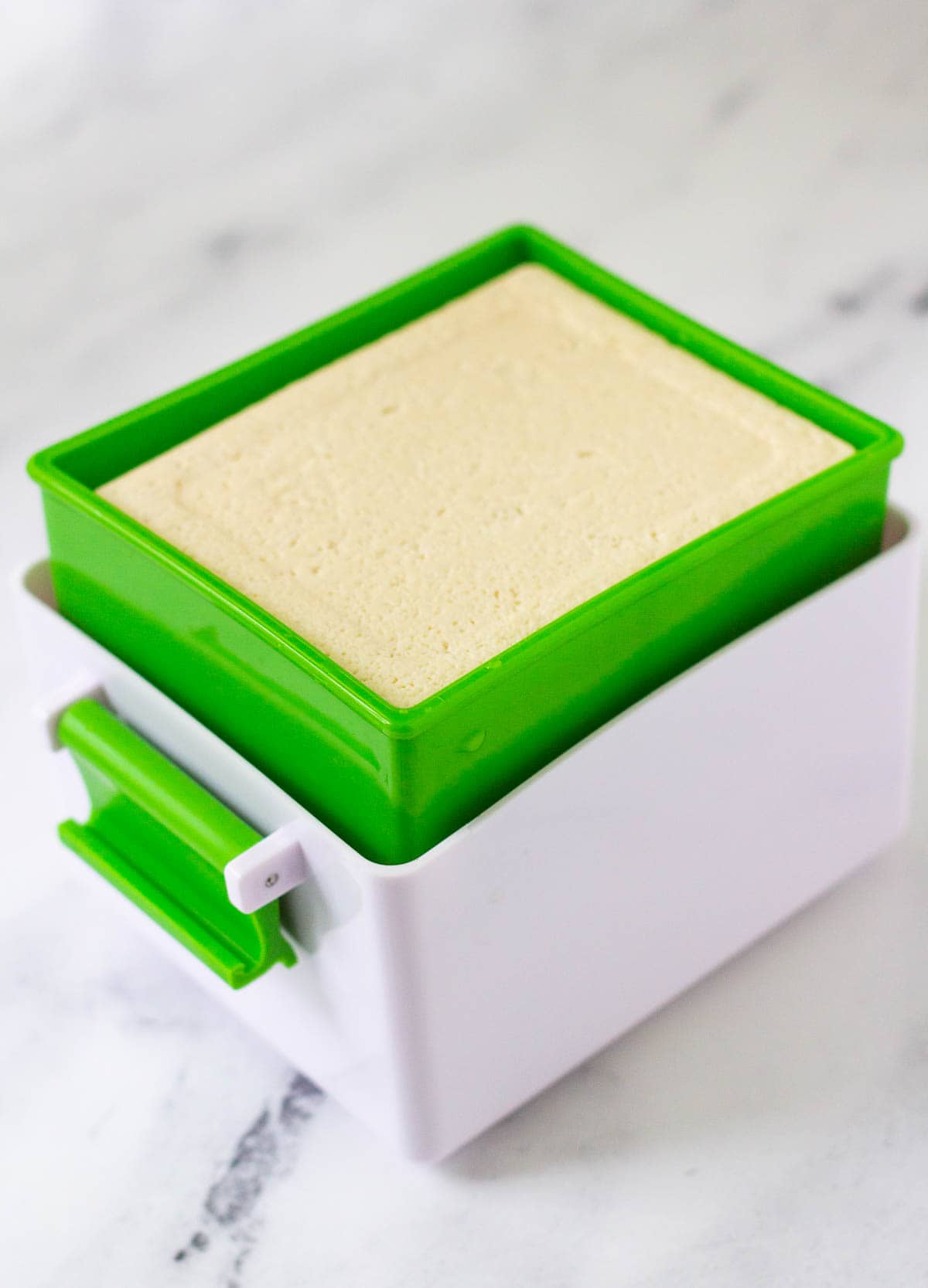 Tofu block inside of tofu press.