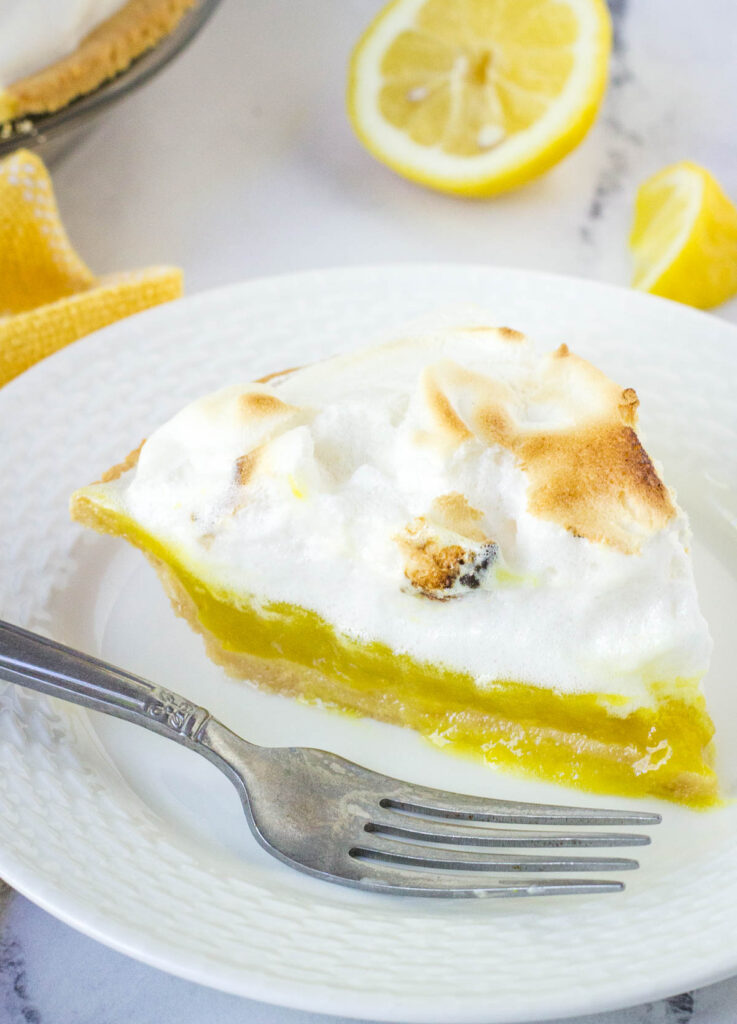 slice of vegan lemon meringue pie on white plate with fork