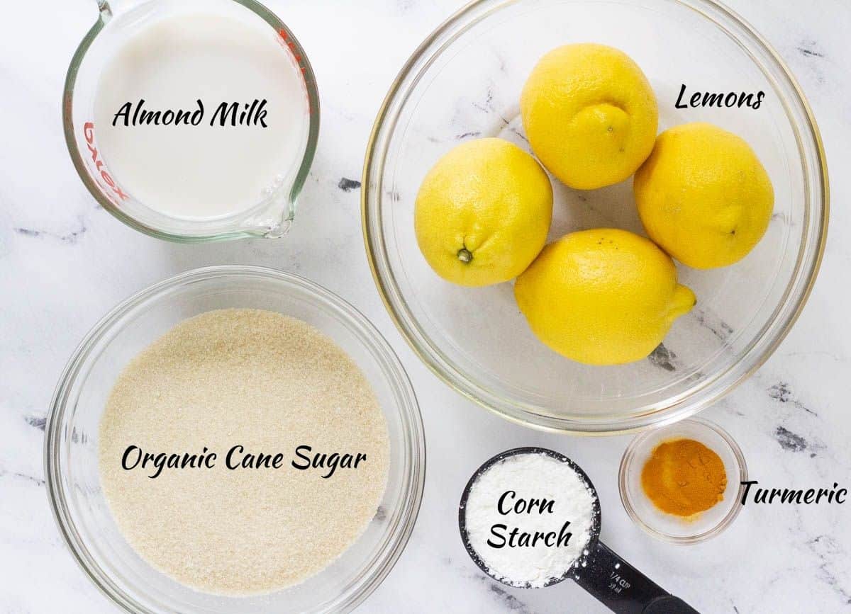 Ingredients for vegan lemon curd in containers: lemons, turmeric, corn starch, cane sugar and almond milk.