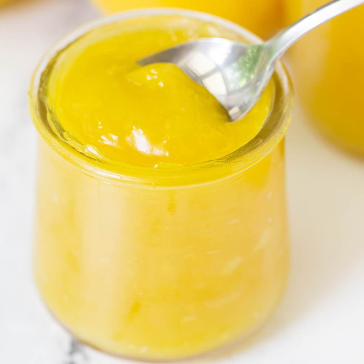 vegan lemon curd in small glass jar with spoon