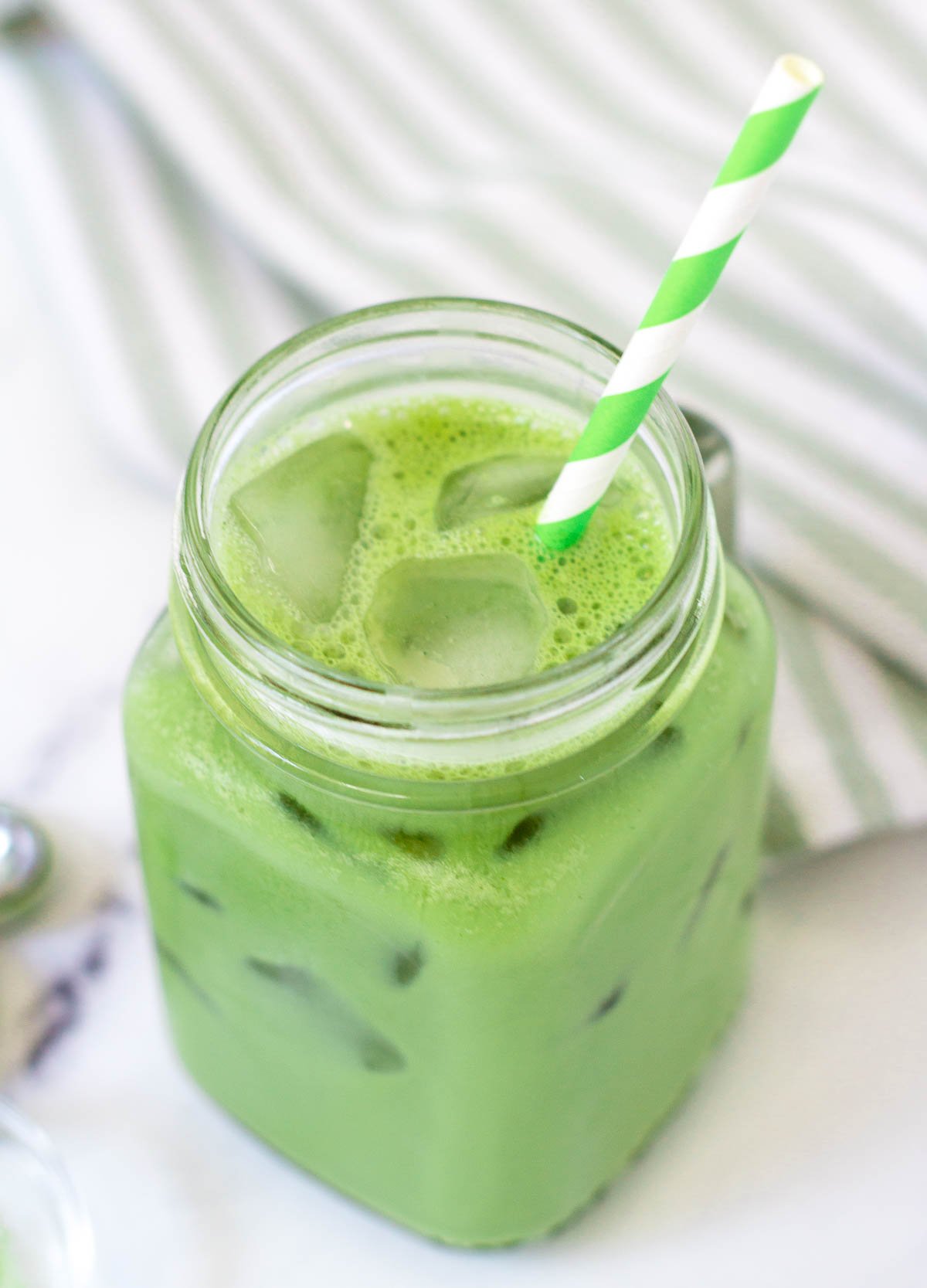 iced matcha latte in glass mug with paper straw