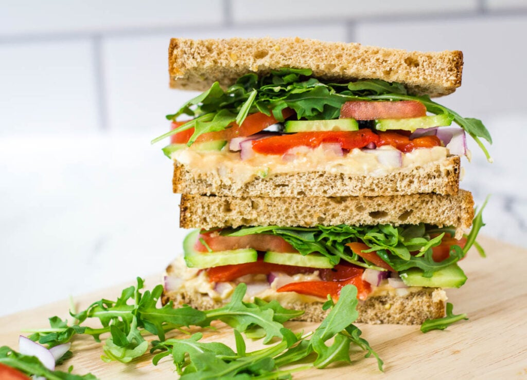 veggie sandwich with arugula, tomato, cucumber, red onion, hummus, and red pepper on whole wheat