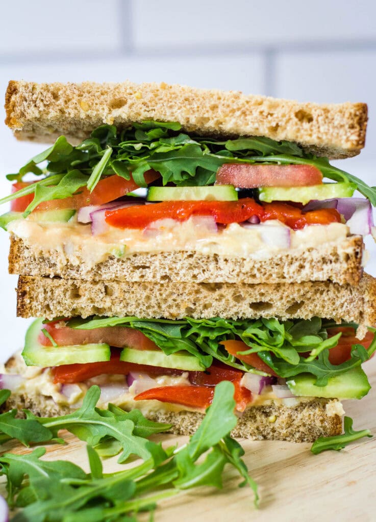 copycat Panera mediterranean veggie sandwich with arugula, tomato, cucumber, red onion, hummus, and red pepper on whole wheat