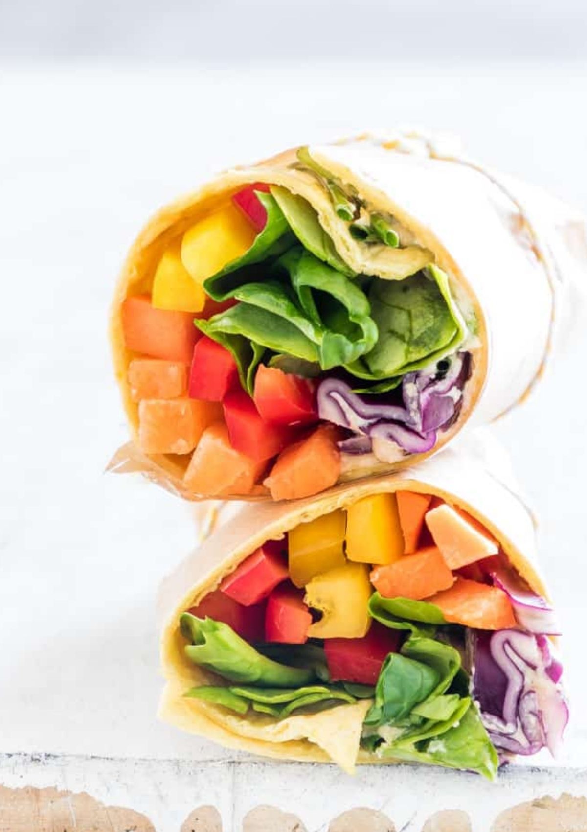 Rainbow veggie hummus wrap sliced in half and stacked