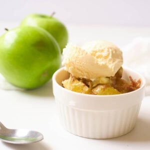 Baked air fryer apples in small ramekin, topped with vanilla ice cream.