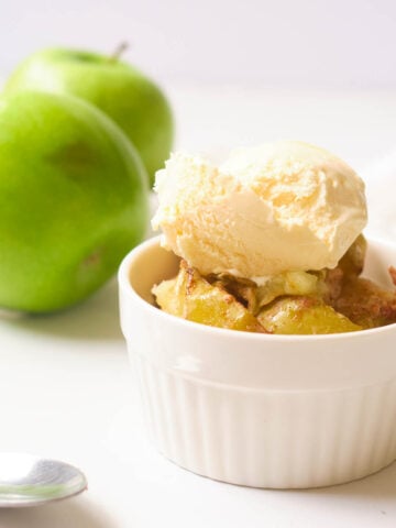 Baked air fryer apples in small ramekin, topped with vanilla ice cream.