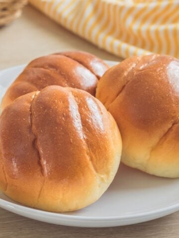 Three bread rolls on white plate.