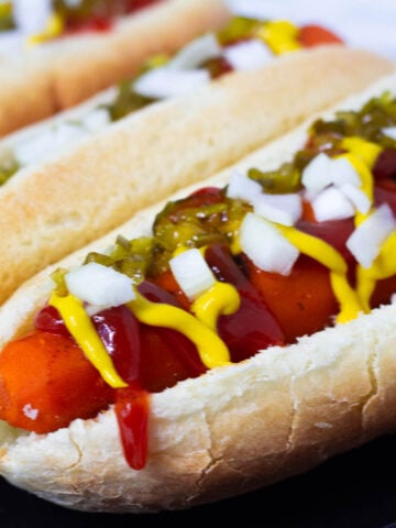 Carrot dogs in bun topped with ketchup, mustard, relish, and onion.