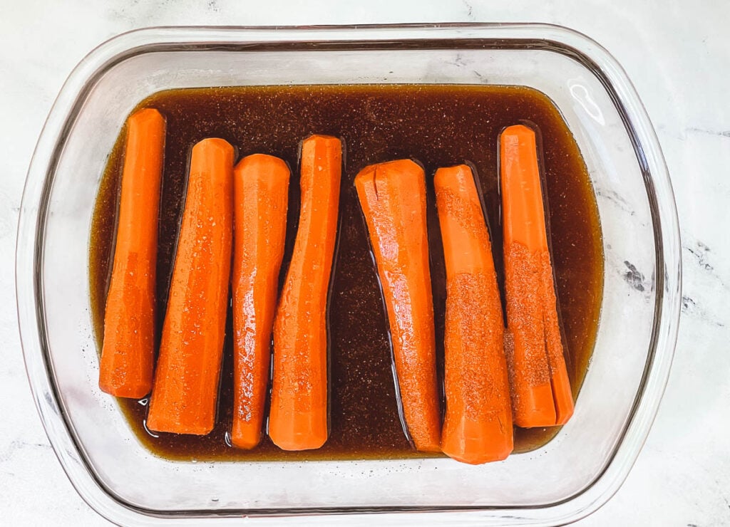 Carrots marinating in shallow glass dish.