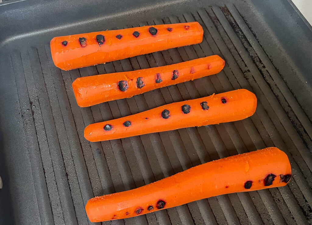 Carrots sticks grilling on grill pan.