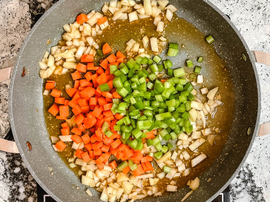 Diced onions, carrots, and celery in pot with vegetable stock.