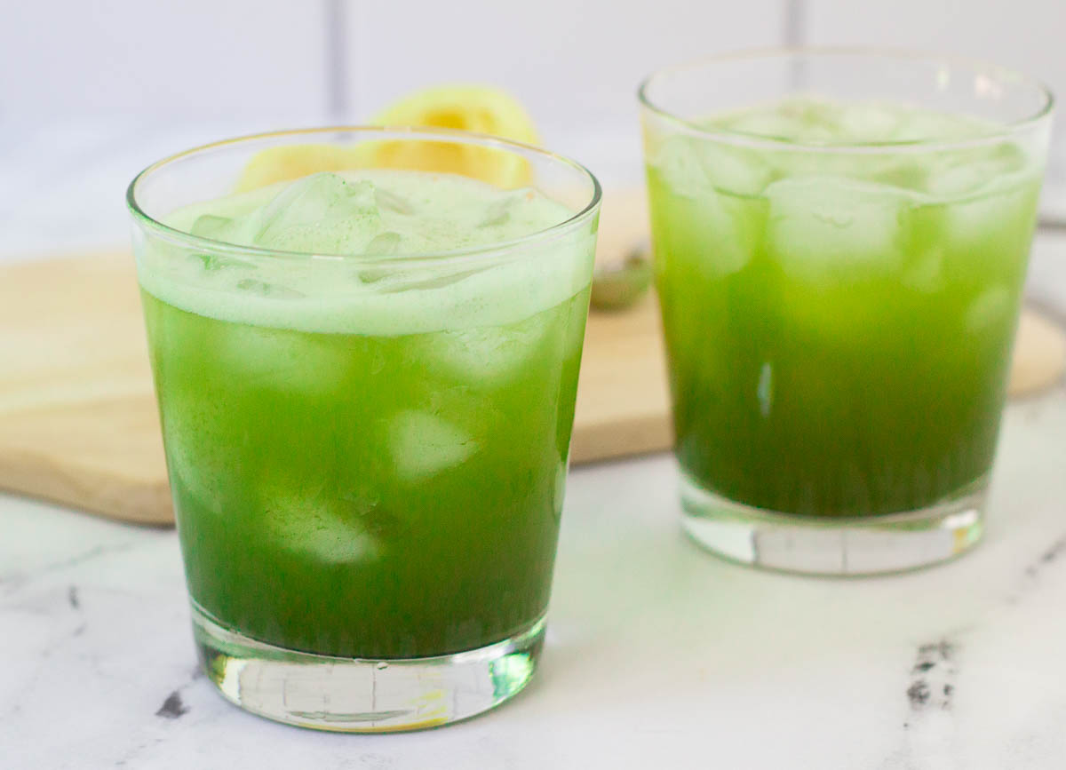Two glasses of matcha lemonade on countertop.