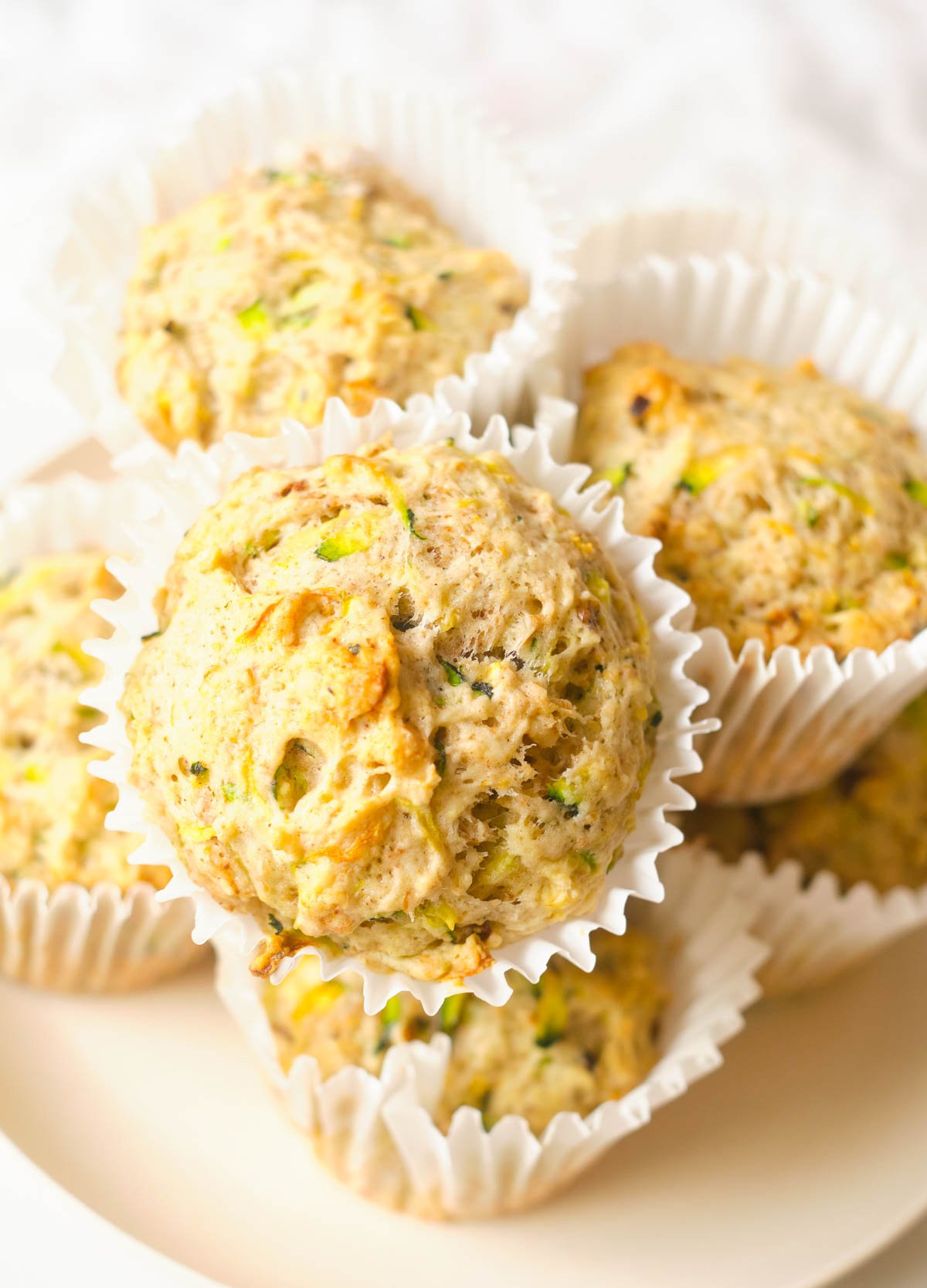 Zucchini muffins stacked on plate. 