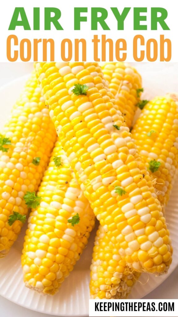 Cooked corn on the cob on a white plate, topped with fresh parsley.