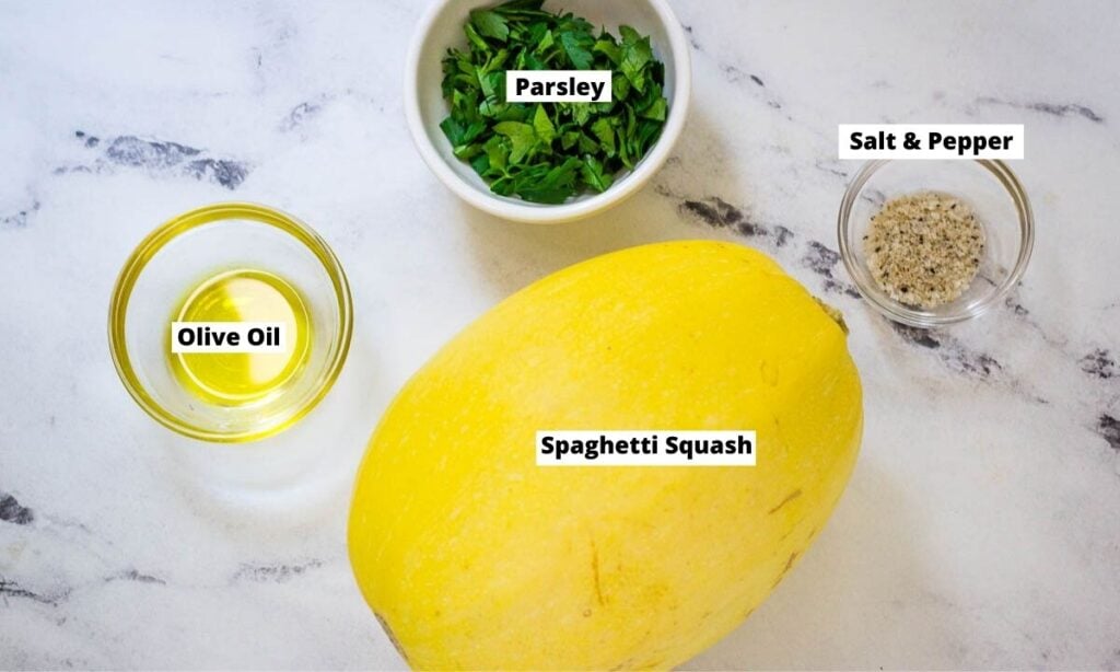 Spaghetti squash, chopped parsley, olive oil, salt and pepper on counter top.
