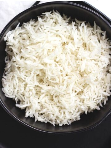 Long grain white rice in black bowl.