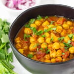 Chana masala topped with cilantro in black bowl.