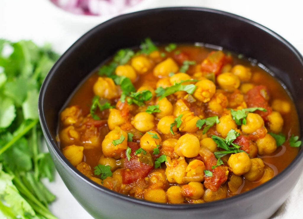 Chana masala topped with cilantro in black bowl.