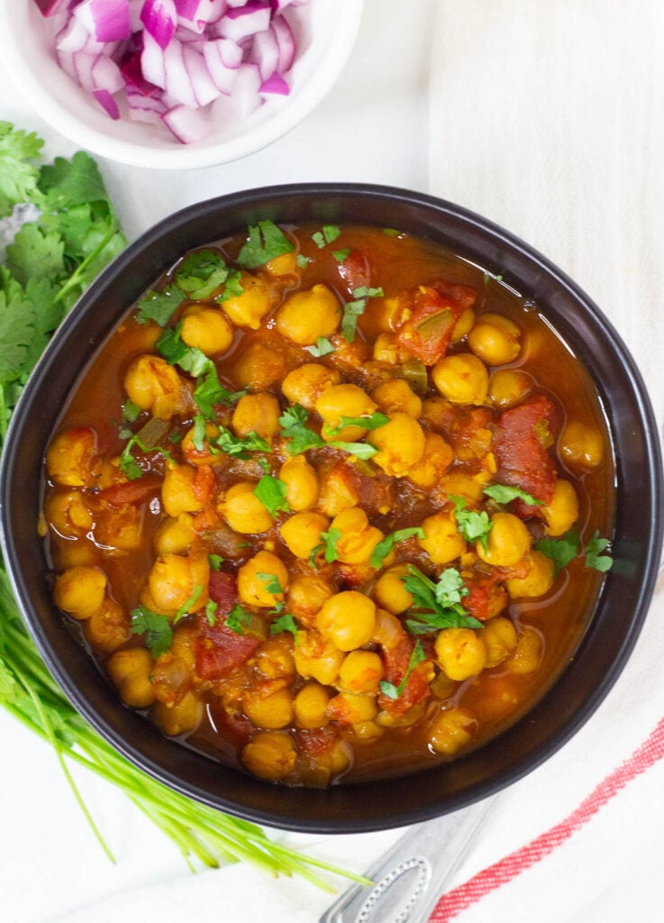 Chana Masala topped with cilantro in black bowl.