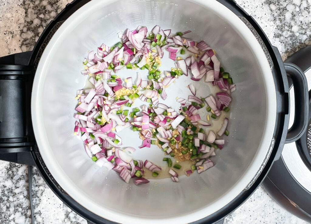 Diced red onion, garlic, and jalapeño sauté in instant pot.