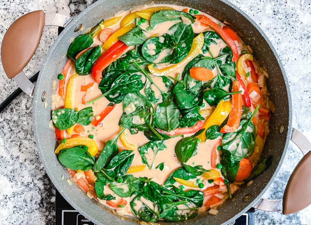 Vegan thai red curry with added spinach leaves that haven't wilted.