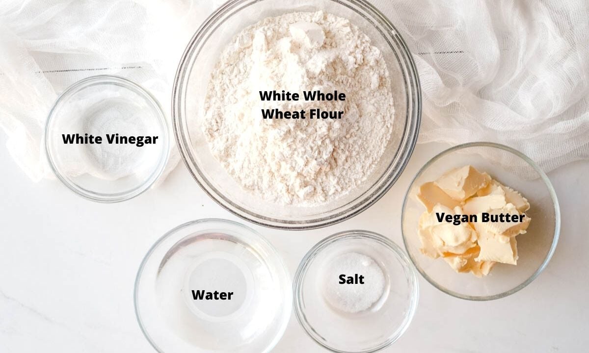 White flour, vegan butter, salt, water, and white vinegar in small bowls. 