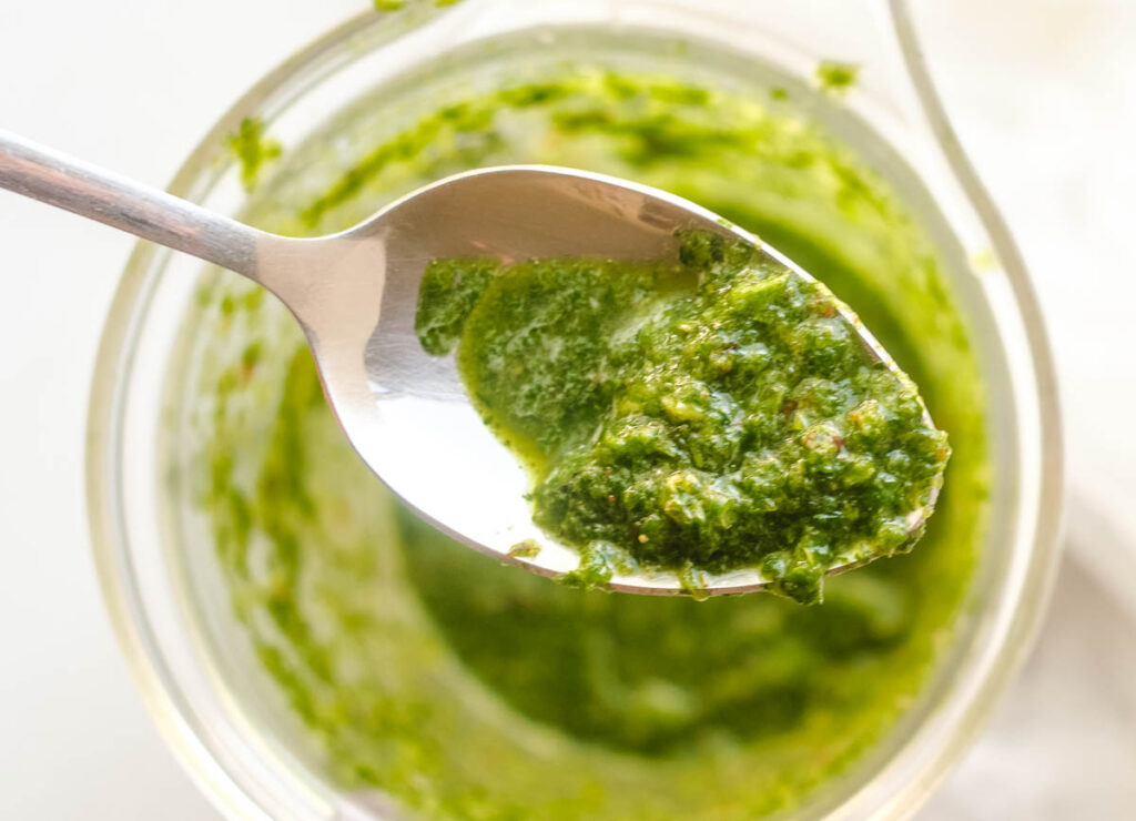 Chimichurri sauce lifted from blender on spoon.