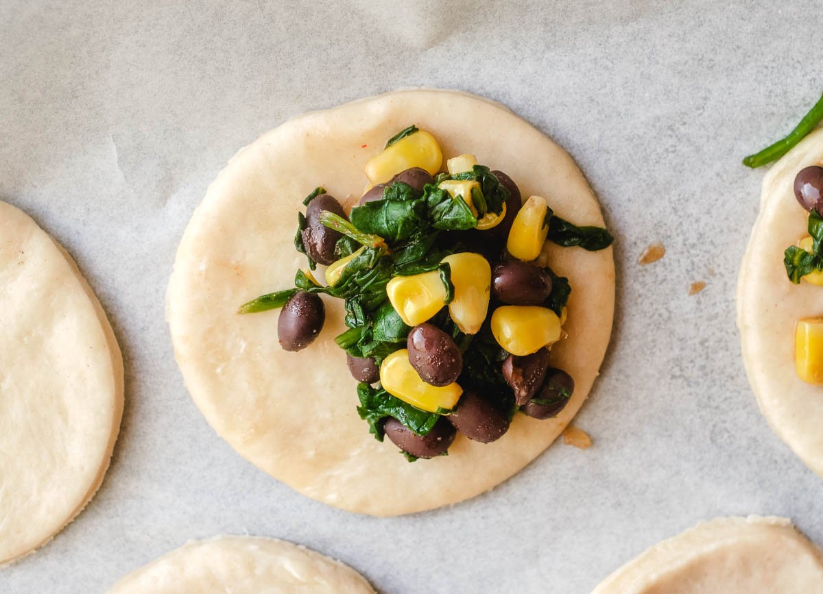 Black bean, spinach, and corn filling on dough circle.