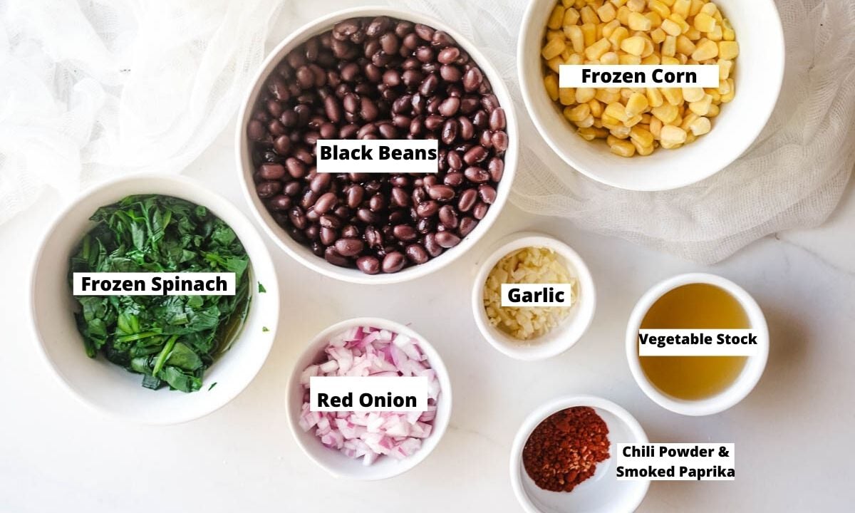 Black beans, frozen corn, frozen spinach, red onion, garlic, vegetable stock, chili powder, and paprika in small bowls.