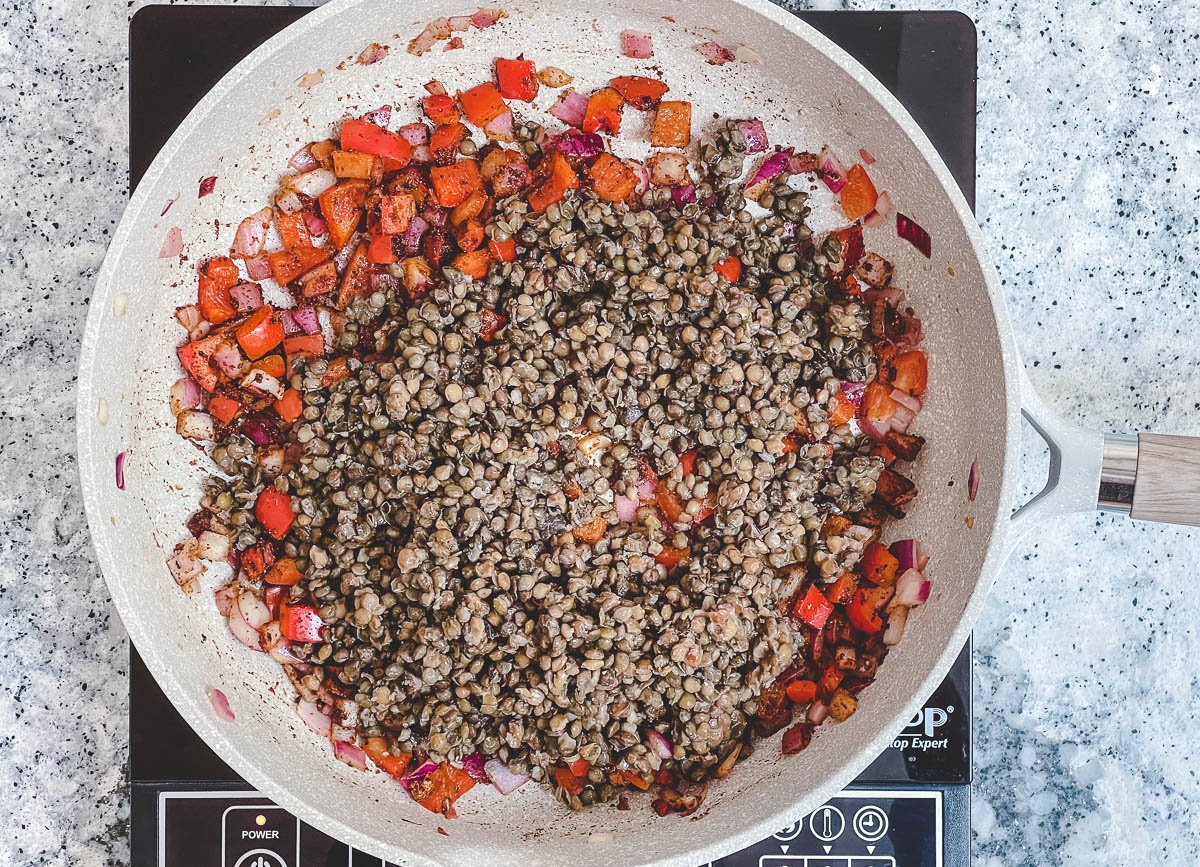 Brown lentils added to pan with sautéd red pepper, and red onion.