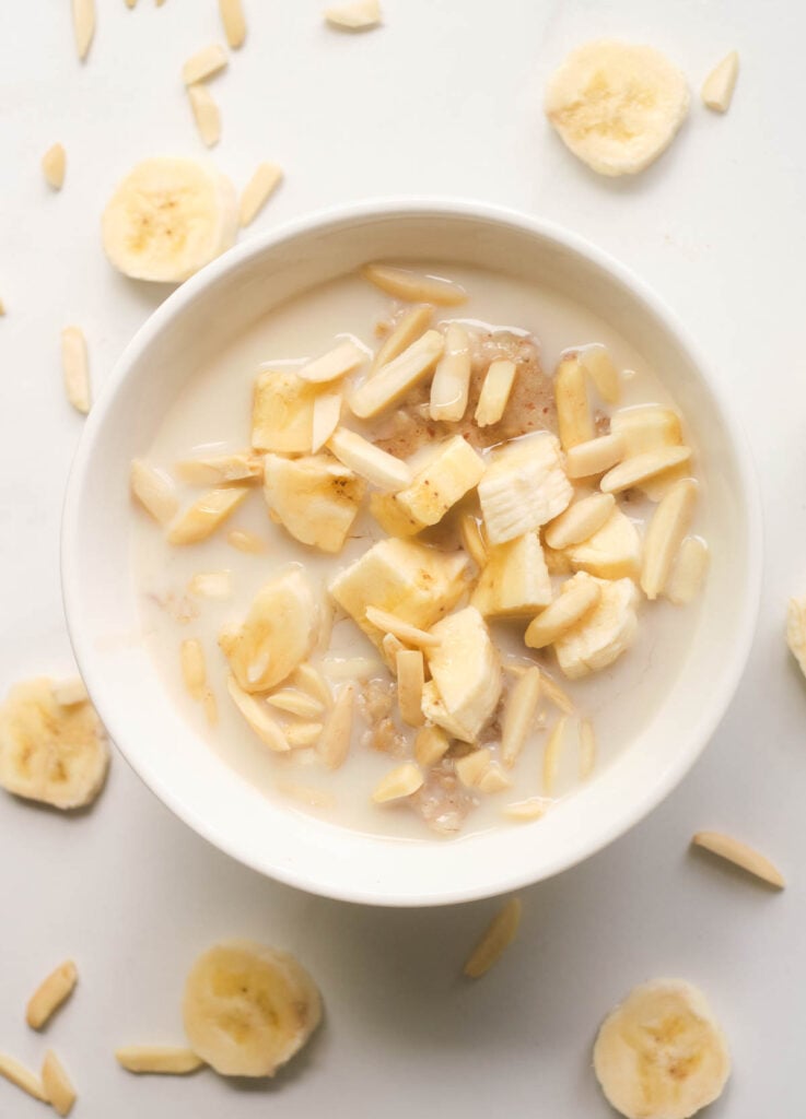 Bowl of oats topped with chopped banana and slivered almonds.