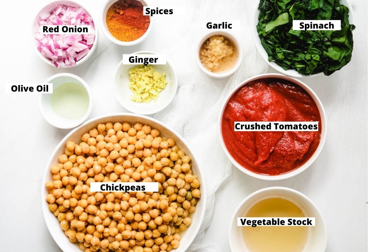 Ingredients for chickpea spinach curry: spinach, crushed tomatoes, vegetable stock, chickpeas, ginger, olive oil, garlic, spices, red onion.