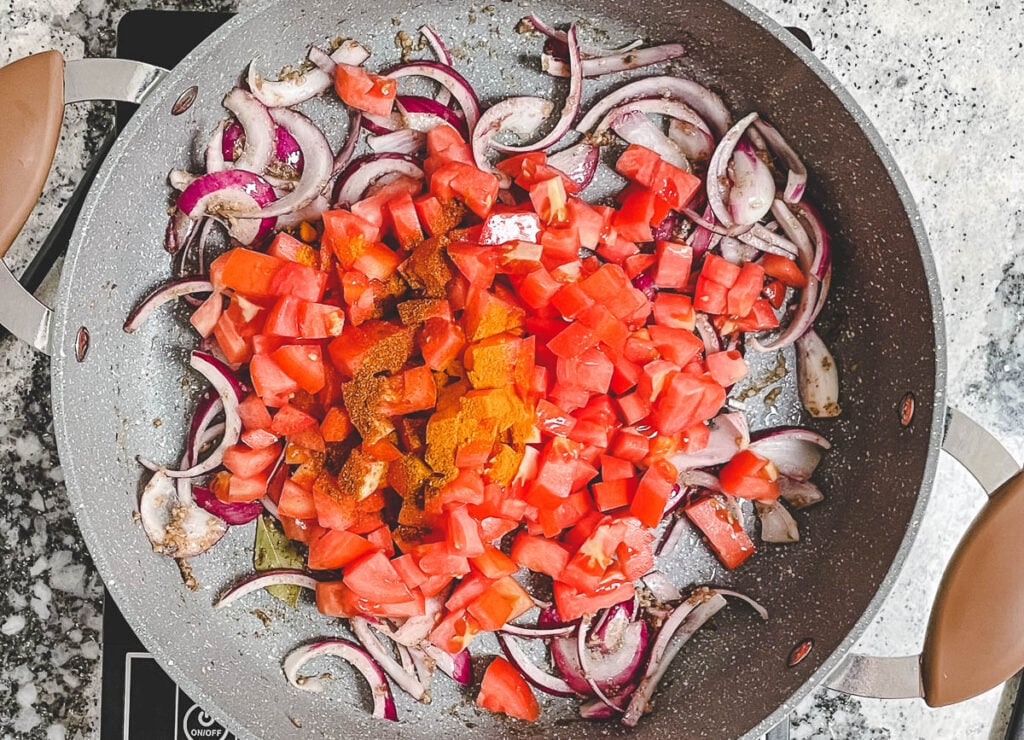 Onions, diced tomatoes, and spices in pot.