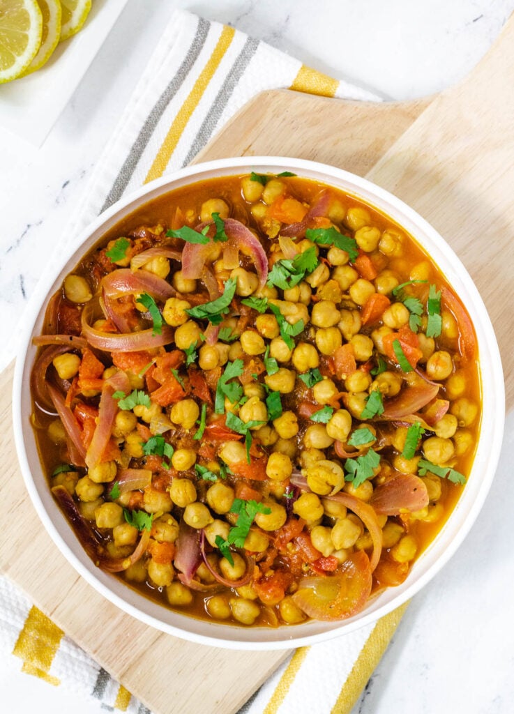 Punjabi chole with chickpeas and garnished with cilantro in wide white bowl.