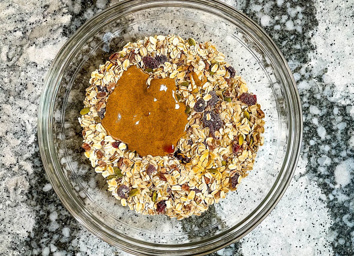 Granola ingredients and almond butter in a glass mixing bowl.