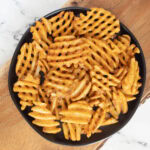 Air fryer waffle fries on black plate.