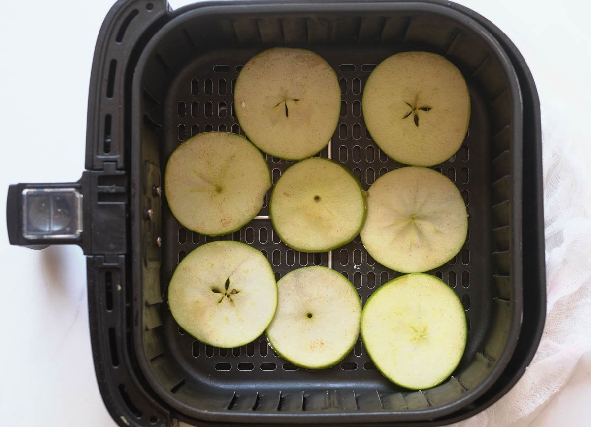 Thinly sliced apple rounds in air fryer basket. 