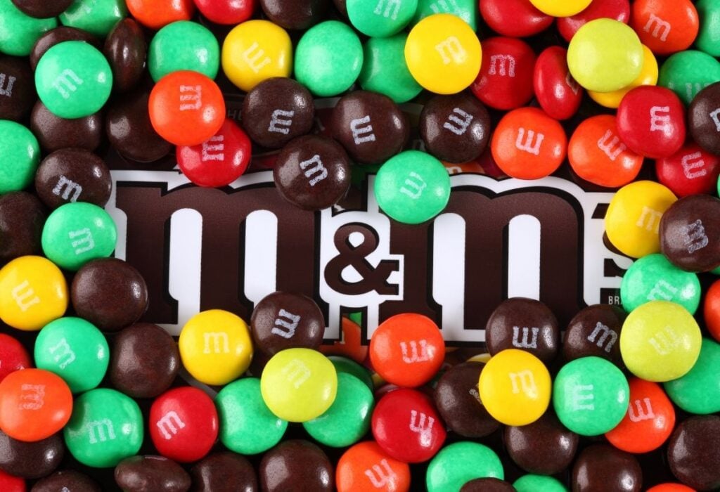 M&M candy bag surrounded by small M&M candies.