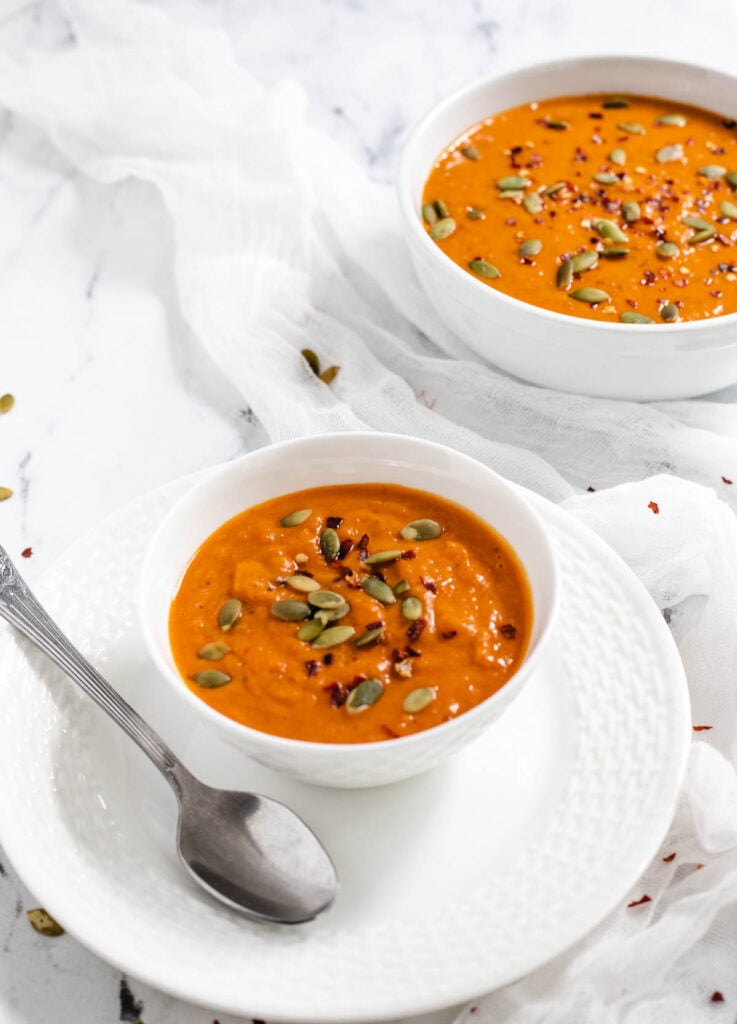 Roasted butternut squash soup in white bowl with serving spoon. 