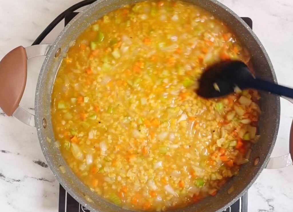 Stirring cooked lentil soup in pot. 