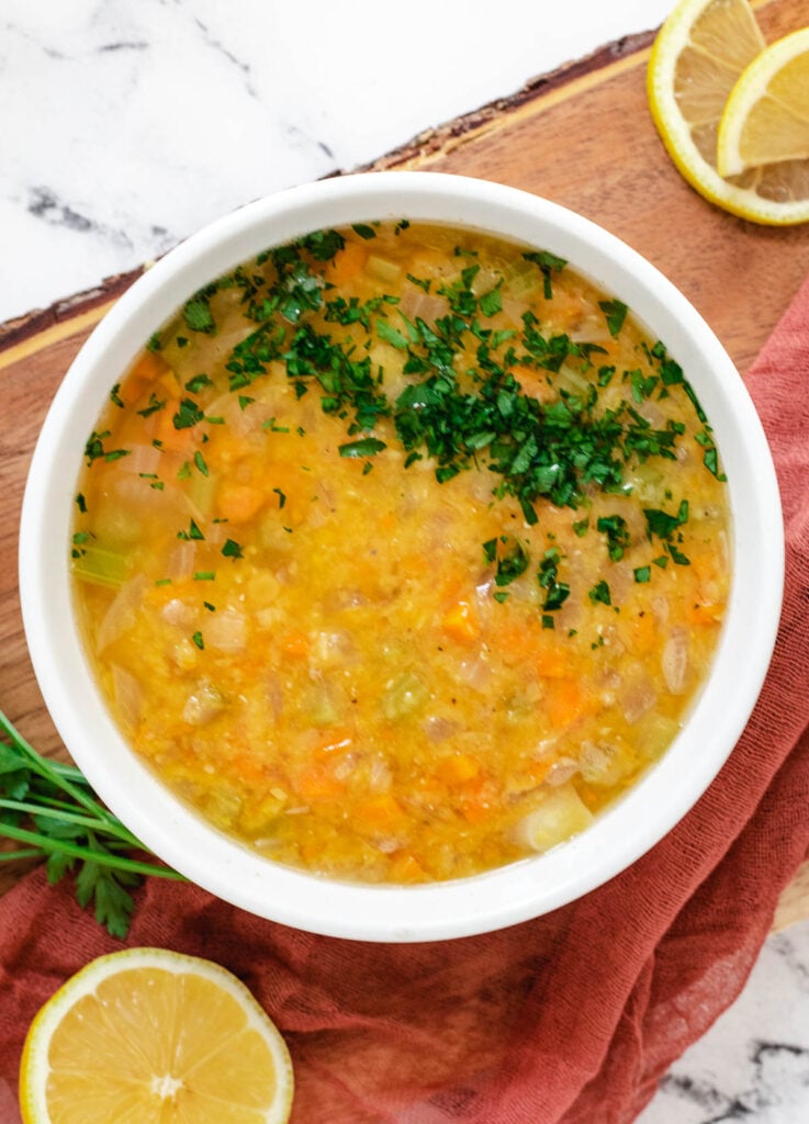 Lebanese lentil soup in white bowl topped with chopped parsley.